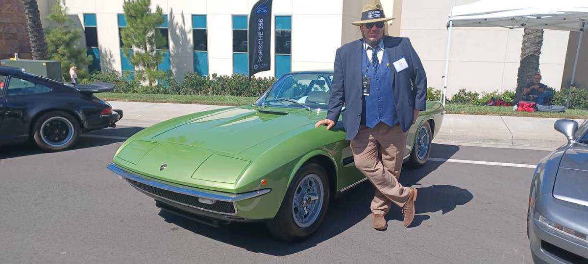 Green sports car with man leaning against the side of it