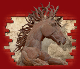 Horse sculpture bursting through red brick wall
